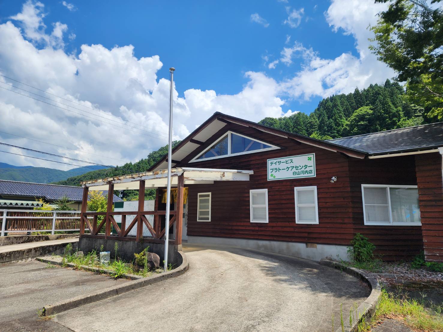 山を背景にした木造のプラトーケアセンター白山河内店の外観